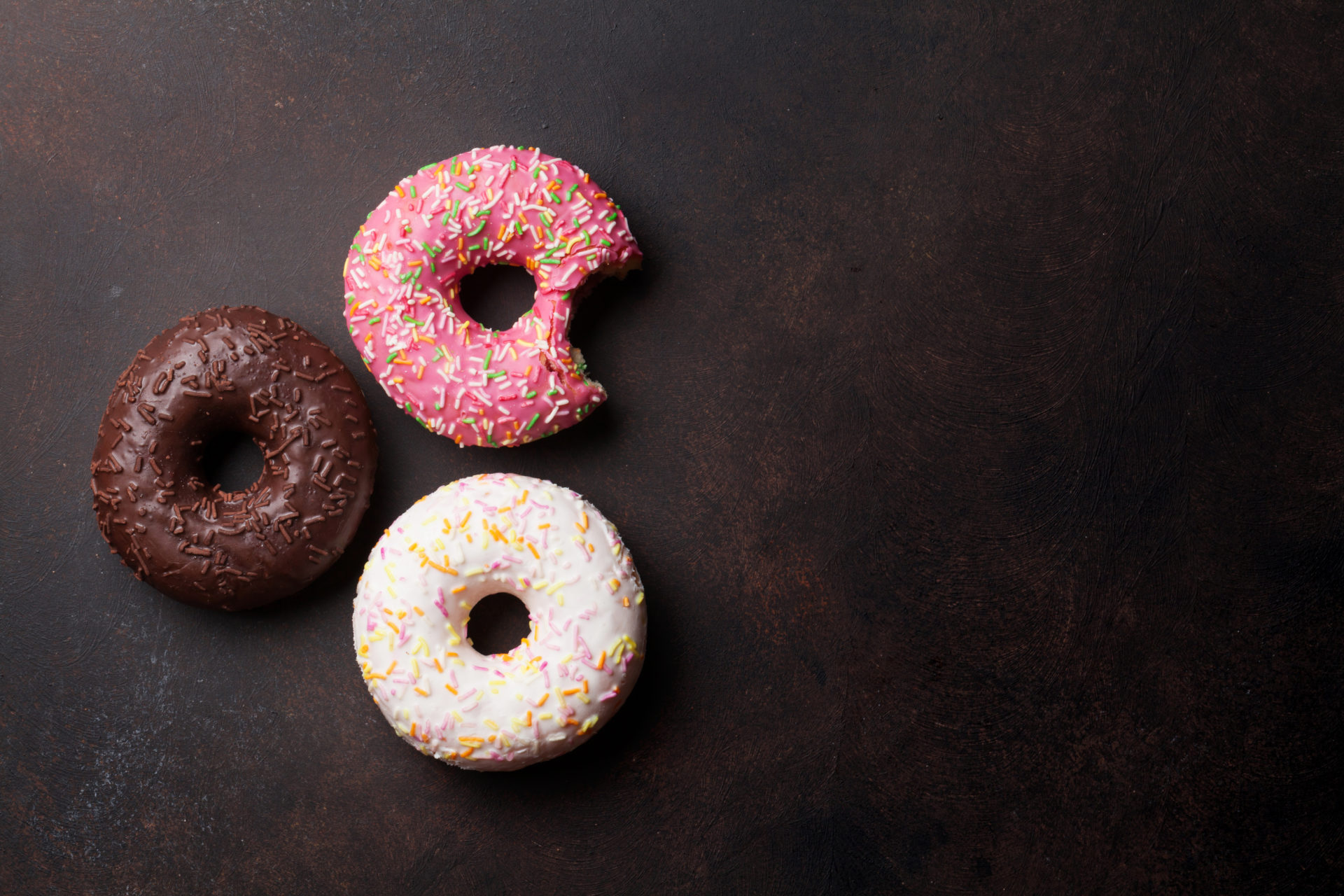 Colorful Donuts Colorful donuts on stone table. Top view with copy space